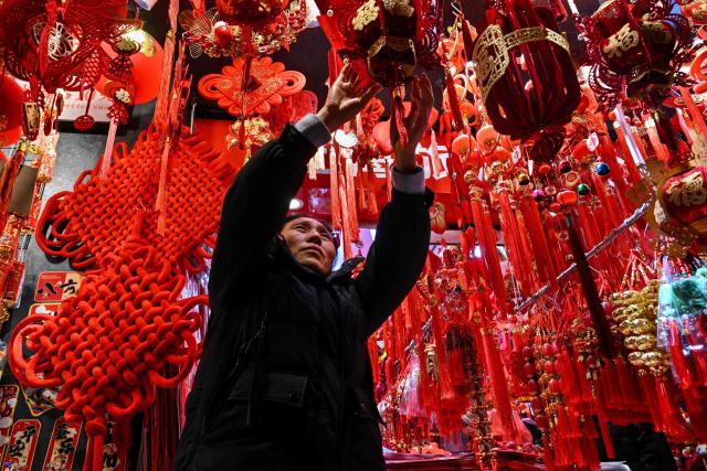 A vendor arranges decorations for Chinese New Year next to Yu Garden at his shop in Shanghai on January 21, 2026. (Photo by Hector RETAMAL / AFP)