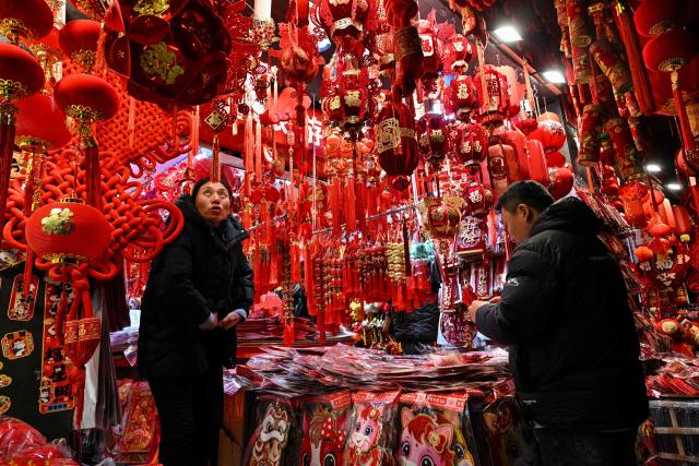 A vendor arranges decoration items for Chinese New Year next to Yu Garden at his shop in Shanghai on January 21, 2026. (Photo by Hector RETAMAL / AFP)