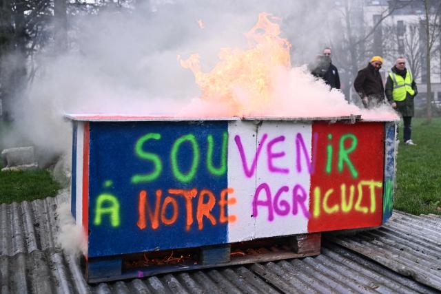 Protestors stand beside a burning fake coffin adorned with graffiti which translates as 'in the memory of our agriculture' set a light during a protest against the free trade agreement between the European Union and the Mercosur countries, in Nantes, western France on January 21, 2026. (Photo by Sebastien Salom-Gomis / AFP)
