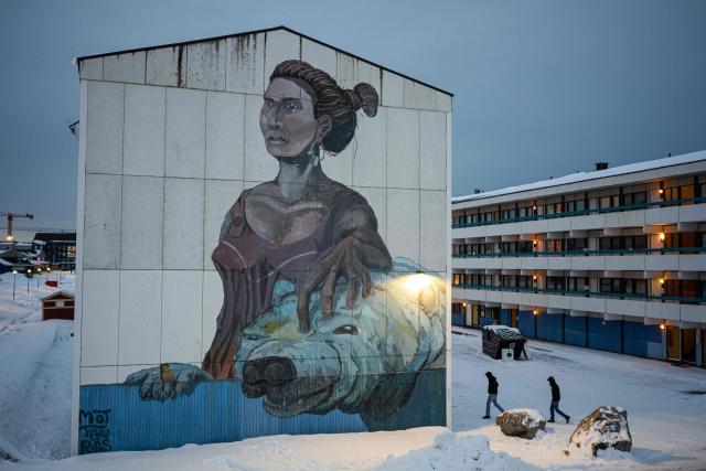 Residents walk past a large mural depicting a woman and a polar bear on the side of an apartment building in Nuuk, Greenland, on January 21, 2026. (Photo by Jonathan NACKSTRAND / AFP)