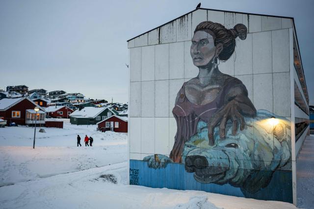 People walk past a large mural depicting a woman and a polar bear on the side of an apartment building in Nuuk, Greenland, on January 21, 2026. (Photo by Jonathan NACKSTRAND / AFP)