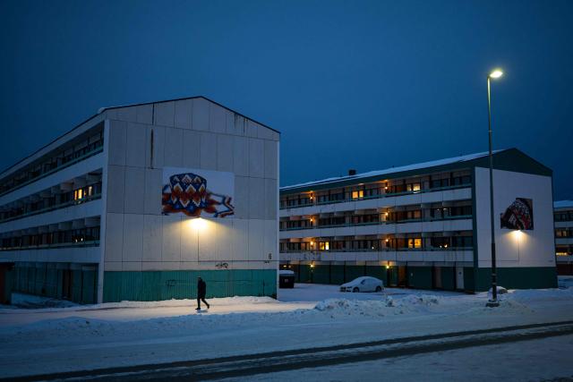A pedestrian walks past apartment buildings decorated with murals in Nuuk, Greenland, on January 21, 2026. (Photo by Jonathan NACKSTRAND / AFP)