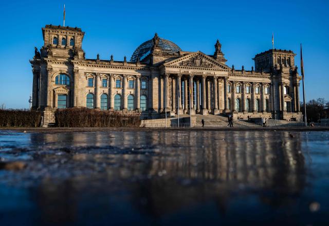 The Reichstag building, which houses Germany's lower house of parliament (Bundestag), is reflected in a sheet of ice in Berlin on January 21, 2026. (Photo by John MACDOUGALL / AFP)