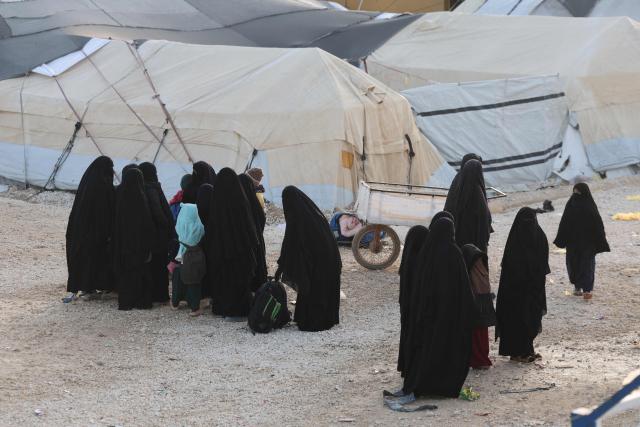 Children and women, relatives of suspected Islamic State jihadists, walk inside Al-Hol camp in the desert region of Syria's northeastern Hasakeh province on January 21, 2026. Syria's army entered the vast Al-Hol camp that houses relatives of suspected Islamic State jihadists after Kurdish forces withdrew from the site, said an AFP journalist at the scene. The camp in a desert region of Hasakeh province holds around 24,000 people, including some 6,200 women and children from around 40 nationalities. (Photo by OMAR HAJ KADOUR / AFP)