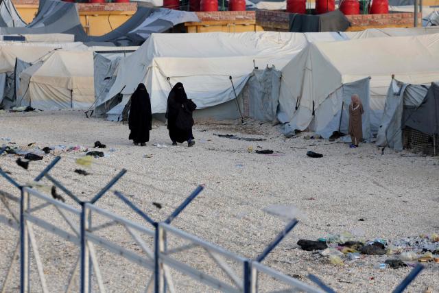 Two women, relatives of suspected Islamic State jihadists, walk inside Al-Hol camp in the desert region of Syria's Hasakeh province on January 21, 2026. Syria's army entered the vast Al-Hol camp that houses relatives of suspected Islamic State jihadists after Kurdish forces withdrew from the site, said an AFP journalist at the scene. The camp in a desert region of Hasakeh province holds around 24,000 people, including some 6,200 women and children from around 40 nationalities. (Photo by OMAR HAJ KADOUR / AFP)