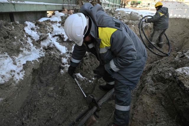 Workers from Ukraine's largest energy provider DTEK carry out emergency repairs of a power line in freezing conditions following Russian missile and drone attacks on Ukrainian energy infrastructure in Kyiv on January 20, 2026, amid the Russian invasion in Ukraine. (Photo by Genya SAVILOV / AFP)