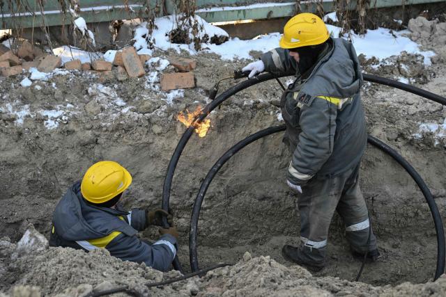 TOPSHOT - Workers from Ukraine's largest energy provider DTEK carry out emergency repairs of a power line in freezing conditions following Russian missile and drone attacks on Ukrainian energy infrastructure in Kyiv on January 20, 2026, amid the Russian invasion in Ukraine. (Photo by Genya SAVILOV / AFP)