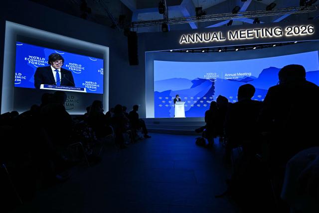 Argentina’s President Javier Milei is seen on a big screen as he speaks during the World Economic Forum (WEF) annual meeting in Davos on January 21, 2026. The World Economic Forum takes place in Davos from January 19 to January 23, 2026. (Photo by Fabrice COFFRINI / AFP)