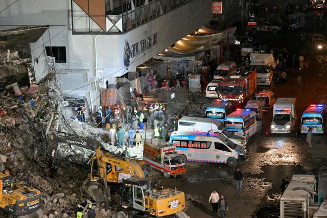 Rescue workers search for bodies among the rubble after a massive fire broke out at a shopping mall in Karachi on January 21, 2026. Pakistani rescuers scoured the charred remains of a Karachi mall on January 21 for dozens missing after a huge blaze destroyed the complex, while relatives gave DNA samples to aid the search. (Photo by Asif HASSAN / AFP)