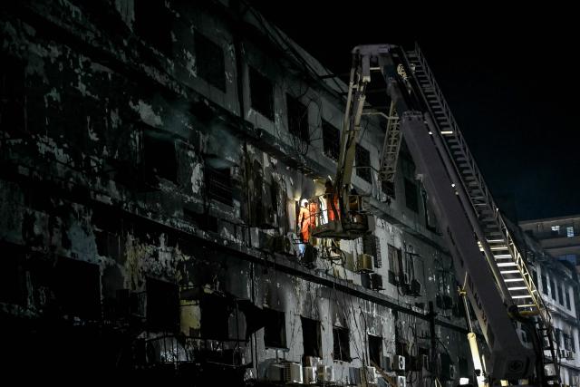 Rescue workers search for bodies among the rubble after a massive fire broke out at a shopping mall in Karachi on January 21, 2026. Pakistani rescuers scoured the charred remains of a Karachi mall on January 21 for dozens missing after a huge blaze destroyed the complex, while relatives gave DNA samples to aid the search. (Photo by Asif HASSAN / AFP)