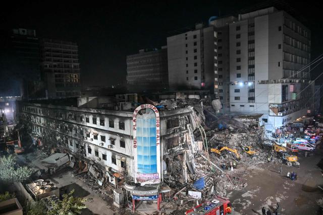 Rescue workers search for bodies among the rubble after a massive fire broke out at a shopping mall in Karachi on January 21, 2026. Pakistani rescuers scoured the charred remains of a Karachi mall on January 21 for dozens missing after a huge blaze destroyed the complex, while relatives gave DNA samples to aid the search. (Photo by Asif HASSAN / AFP)