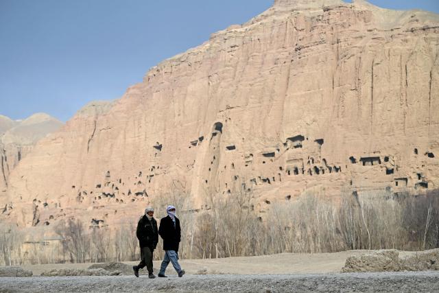 Afghan men walk past the destroyed Shama Buddha statues in Bamiyan province on January 20, 2026. (Photo by Wakil KOHSAR / AFP)