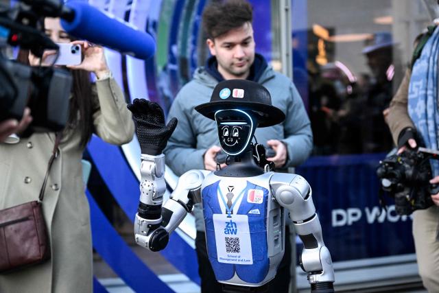 A photograph taken on January 21, 2026 shows a Unitree G1 Robotic Humanoid model dressed waving to the press in the street of the Alpine resort of Davos during the World Economic Forum (WEF) annual meeting. The World Economic Forum takes place in Davos from January 19 to January 23, 2026. (Photo by INA FASSBENDER / AFP)