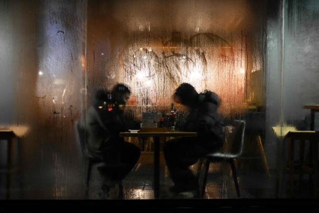 TOPSHOT - People sit in a cafe in Kyiv on January 21, 2026, amid the Russian invasion of Ukraine. (Photo by Sergei GAPON / AFP)