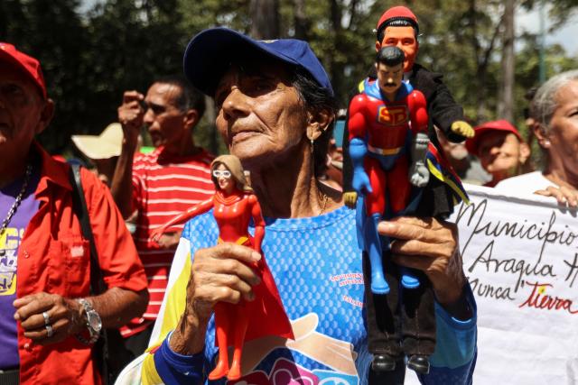 A woman shows action figures during a demonstration by elder people to demand the release of ousted Venezuelan President Nicolas Maduro and his wife Cilia Flores in Caracas on January 21, 2026. (Photo by Pedro MATTEY / AFP)