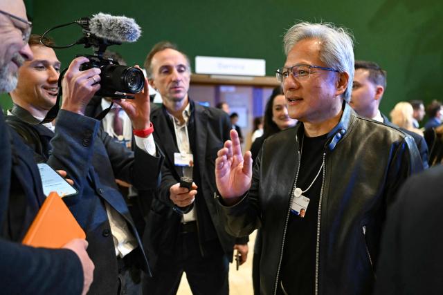 Nvidia founder and CEO Jensen Huang gestures, flanked by journalists as he departs after a business leaders reception with the US President on the sidelines of the World Economic Forum (WEF) annual meeting in Davos on January 21, 2026. The World Economic Forum takes place in Davos from January 19 to January 23, 2026. (Photo by Fabrice COFFRINI / AFP)