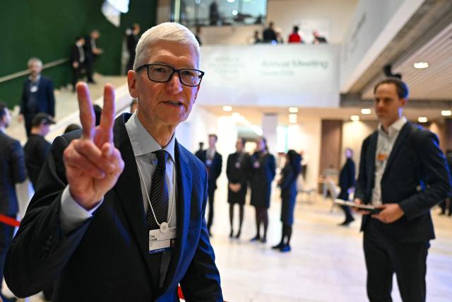 US businessman Tim Cook gestures flanked by journalists as he departs after a business leaders reception with the US President on the sidelines of the World Economic Forum (WEF) annual meeting in Davos on January 21, 2026. The World Economic Forum takes place in Davos from January 19 to January 23, 2026. (Photo by Fabrice COFFRINI / AFP)