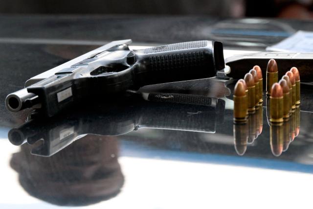 A seized gun and bullets are displayed during a security operation in Quito's financial district on January 21, 2026. (Photo by Rodrigo BUENDIA / AFP)