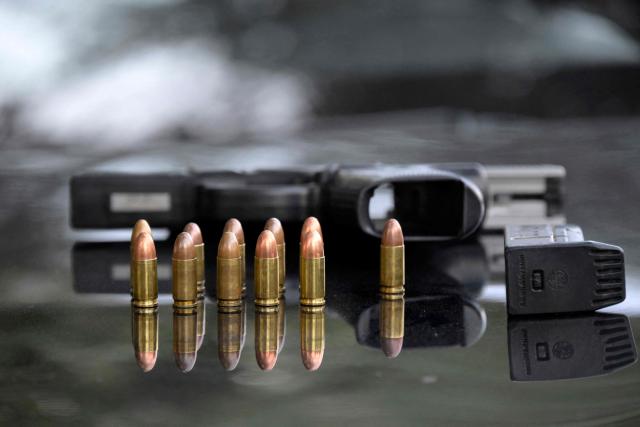 A seized gun and bullets are displayed during a security operation in Quito's financial district on January 21, 2026. (Photo by Rodrigo BUENDIA / AFP)