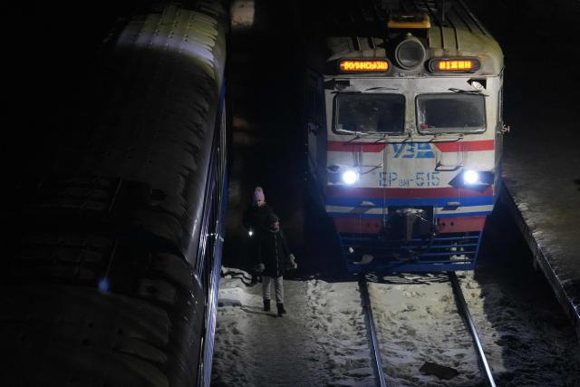 People walk past a train carriage temporarily used as a heating point at a railway station in Brovary, Kyiv region on January 21, 2026, amid the Russian invasion of Ukraine. (Photo by OLEKSII FILIPPOV / AFP)