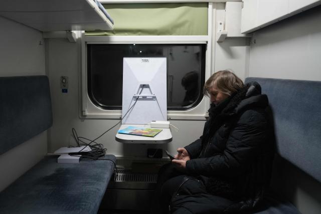 A woman sits in a train carriage temporarily used as a heating point at a railway station in Brovary, Kyiv region on January 21, 2026, amid the Russian invasion of Ukraine. (Photo by OLEKSII FILIPPOV / AFP)