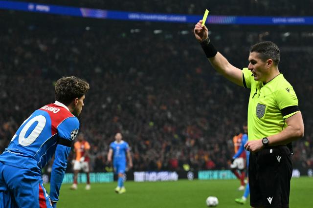 Referee Istvan Kovacs (R) gives a yellow card to Atletico Madrid's Argentine forward #20 Giuliano Simeone during the UEFA Champions League, league phase day 7, football match between Galatasaray and Atletico Madrid at Rams Park in Istanbul, on January 21, 2026. (Photo by Ozan KOSE / AFP)