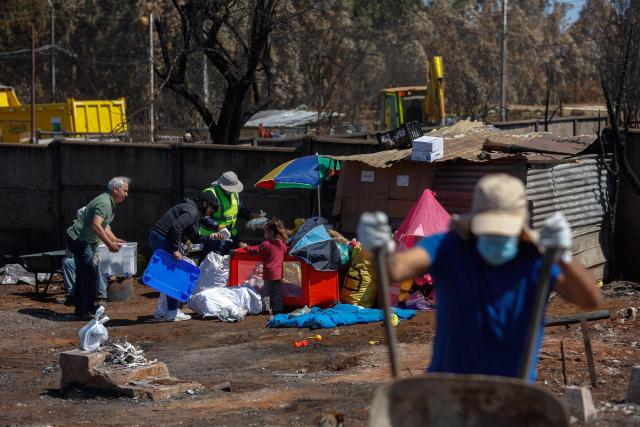 Children receive care following the devastating forest fires that ravaged the area on January 3, in Punta de Parra, near Concepcion, Chile, on January 21, 2026. Police in south-central Chile have arrested a man on suspicion of starting one of the recent wildfires that killed 20 people and razed entire neighborhoods, the government said on January 21. (Photo by Raul BRAVO / AFP)