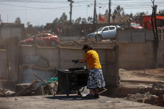 A resident holds a pan from the charred remains of a stove after the devastating wildfires that ravaged the area on January 3, in Punta de Parra, near Concepcion, Chile, on January 21, 2026. Police in south-central Chile have arrested a man on suspicion of starting one of the recent wildfires that killed 20 people and razed entire neighborhoods, the government said on January 21. (Photo by Raul BRAVO / AFP)