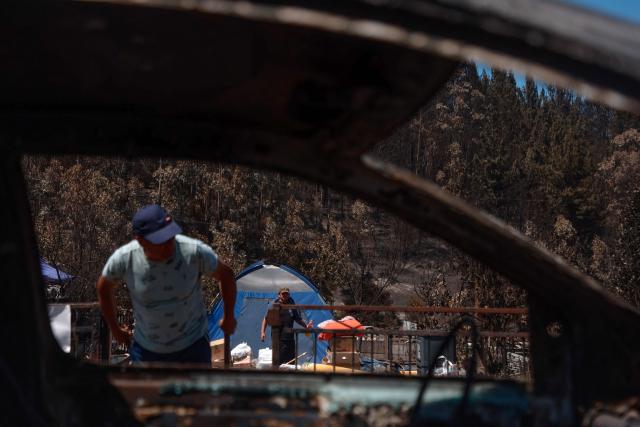 Residents clean debris after the devastating wildfires that ravaged the area on January 3, in Punta de Parra, near Concepcion, Chile, on January 21, 2026. Police in south-central Chile have arrested a man on suspicion of starting one of the recent wildfires that killed 20 people and razed entire neighborhoods, the government said on January 21. (Photo by Raul BRAVO / AFP)