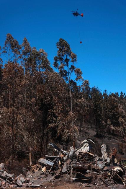 A helicopter transports water to extinguish a forest fire in Punta de Parra, near Concepcion, Chile, on January 21, 2026. Police in south-central Chile have arrested a man on suspicion of starting one of the recent wildfires that killed 20 people and razed entire neighborhoods, the government said on January 21. (Photo by Raul BRAVO / AFP)