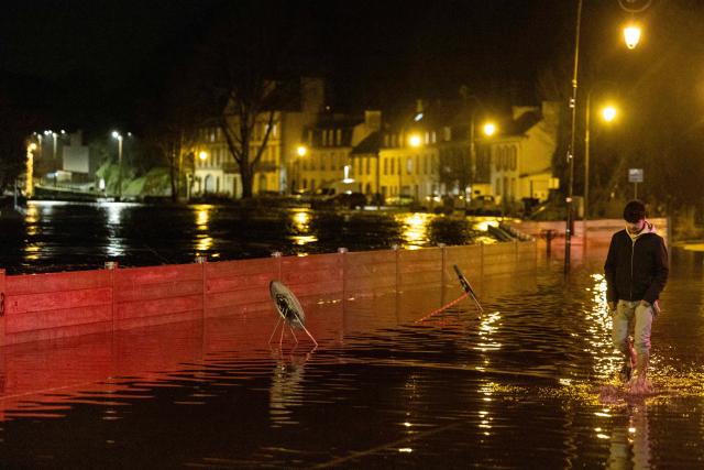 A man walks down a flooded street in Quimperle, western France, on January 21, 2026. Finistere and Morbihan departments of western France were placed on orange alert on January 21, 2026, for “rain and flooding”. (Photo by Fred TANNEAU / AFP)