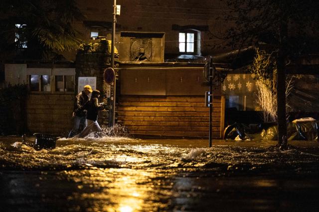 A couple walk down a flooded street in Quimperle, western France, on January 21, 2026. Finistere and Morbihan departments of western France were placed on orange alert on January 21, 2026, for “rain and flooding”. (Photo by Fred TANNEAU / AFP)