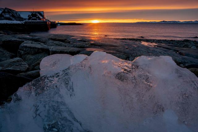 The sun setting over the water is seen from above a translucent ice block in Nuuk, Greenland, on January 21, 2026. (Photo by Mads Claus Rasmussen / Ritzau Scanpix / AFP) / Denmark OUT