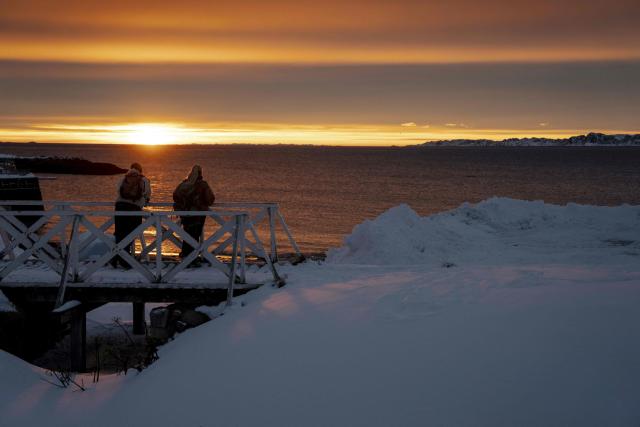 People watch from a bridge over the water at the sunset in Nuuk, Greenland, on January 21, 2026. (Photo by Mads Claus Rasmussen / Ritzau Scanpix / AFP) / Denmark OUT