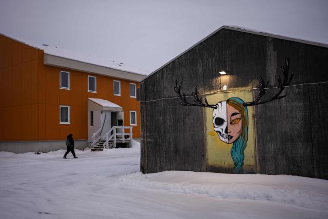 A pedestrian walks past a mural painted on a building in a residential area in Nuuk, Greenland, on January 21, 2026. (Photo by Jonathan NACKSTRAND / AFP)