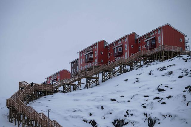 A man walks down a wooden staircase connecting hillside homes to a main road in Nuuk, Greenland, on January 21, 2026. (Photo by Jonathan NACKSTRAND / AFP)