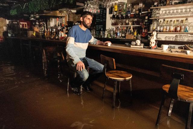 French owner of the hotel-bar "Le Brizeux" Teddy Muller sits on a stool inside his flooded bar in Quimperle, western France, on January 21, 2026. Finistere and Morbihan departments of western France were placed on orange alert on January 21, 2026, for “rain and flooding”. (Photo by Fred TANNEAU / AFP)