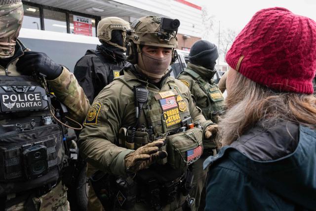 A woman confronts US Border Patrol agents near US Border Patrol commander Gregory Bovino's car at a gas station in Minneapolis, Minnesota on January 21, 2026. The Pentagon has ordered 1,500 US soldiers to prepare for a possible deployment to a state roiled by unrest over an immigration crackdown, US media reported on January 18. The reported preparations come days after President Donald Trump threatened to invoke the Insurrection Act, which enables use of the military to suppress "armed rebellion" or "domestic violence" -- although a day later he said there was no immediate need for it. (Photo by ROBERTO SCHMIDT / AFP)