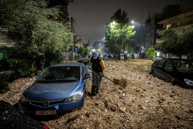A man tries to clean a flooded street covered with rubbles after a heavy rainfalls in Ano Glyfada, southern of Athens, on January 21, 2026. (Photo by Aris MESSINIS / AFP)