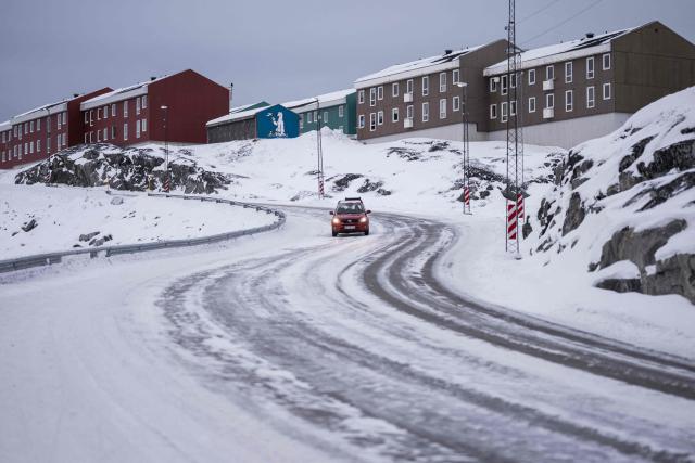 A car drives down a snow-covered road past residential buildings in Nuuk, Greenland, on January 21, 2026. (Photo by Jonathan NACKSTRAND / AFP)