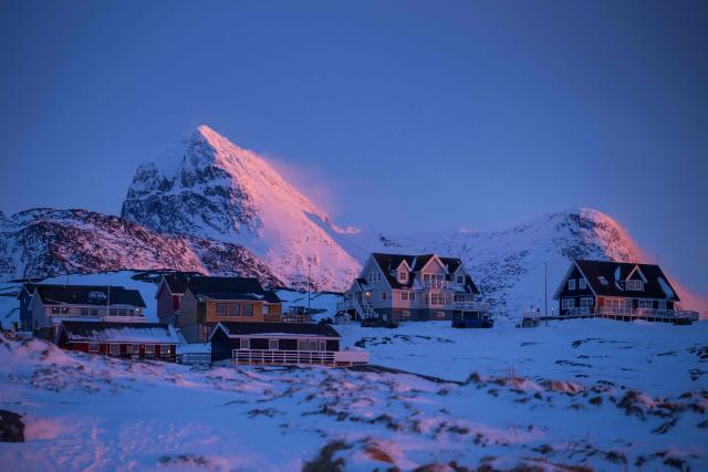 This photograph shows houses beneath snow covered mountains at dusk in Nuuk, Greenland, on January 21, 2026. (Photo by Jonathan NACKSTRAND / AFP)