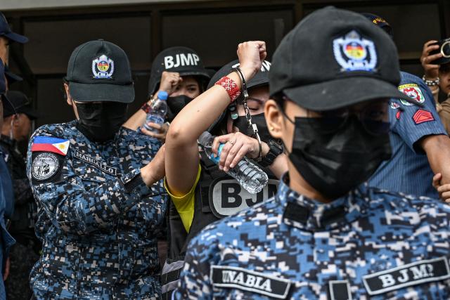Frenchie Mae Cumpio (back, wearing yellow), a detained Filipino journalist, and her former roommate Marielle Domequil (front, wearing yellow) leave Tacloban Regional Trial Court in Leyte island on January 22, 2026, after the promulgation of her court case. Cumpio, who spent nearly six years in a crowded provincial prison, was found guilty of terror financing in a case rights groups and a UN rapporteur had labelled a "travesty of justice". (Photo by Jam STA ROSA / AFP)