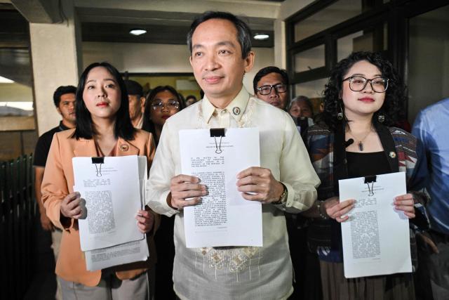 (L-R) House of Representatives Sara Elago, Antonio Tinio and Louise Co show the documents as endorsers of the impeachment complaint against Philippine President Ferdinand Marcos at the House of Representatives in Quezon City, suburban Manila on January 22, 2026. (Photo by TED ALJIBE / AFP)