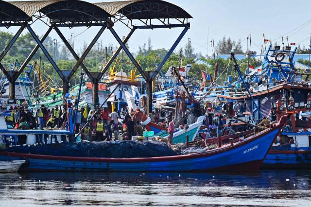 Fishermen unload their nets onto a boat in Banda Aceh on January 22, 2026. (Photo by CHAIDEER MAHYUDDIN / AFP)