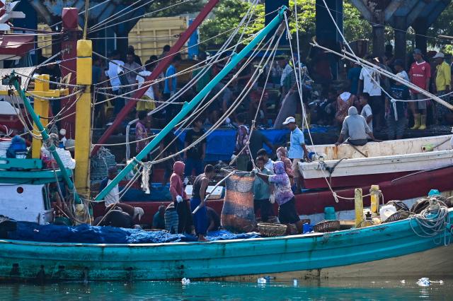 Fishermen unload their nets onto a boat in Banda Aceh on January 22, 2026. (Photo by CHAIDEER MAHYUDDIN / AFP)
