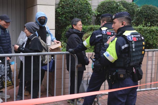 Tang Ngok-kwan (C), a Tiananmen vigil activist and former committee member for Hong Kong Alliance in Support of Patriotic Democratic Movements of China, is seen queueing for the start of the trial of the now-disbanded Hong Kong Alliance with among the defendants three of its leaders, Chow Hang-tung, Albert Ho and Lee Cheuk-yan who for years organised the annual vigil for the victims of the Tiananmen Square massacre in 1989. (Photo by Tommy WANG / AFP)