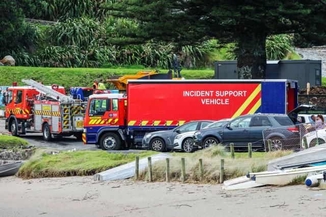 Police and officials stand following a landslide while a search is underway by local emergency services for missing people at Mount Maunganui in Tauranga on January 22, 2026. A landslide smashed into a campsite in rain-swept northern New Zealand leaving multiple people missing, police and rescuers said. (Photo by DJ MILLS / AFP)