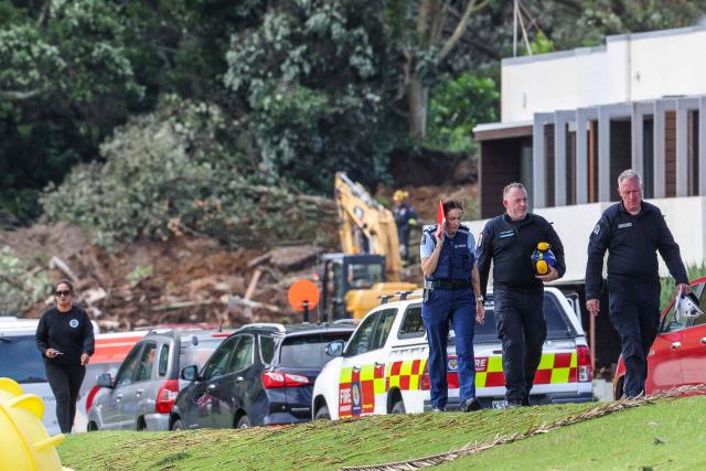 Police and officials walk following a landslide while a search is underway by local emergency services for missing people at Mount Maunganui in Tauranga on January 22, 2026. A landslide smashed into a campsite in rain-swept northern New Zealand leaving multiple people missing, police and rescuers said. (Photo by DJ MILLS / AFP)