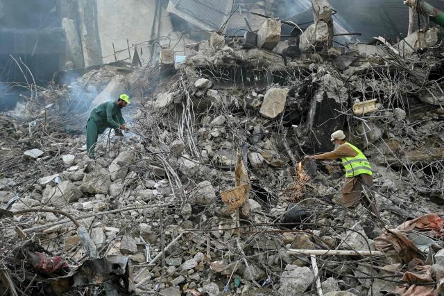 Workers clear debris after a massive fire broke out at a shopping mall in Karachi on January 22, 2026. The death toll from a mall fire in Pakistan's biggest city rose to at least 55 people, a Karachi government official told AFP on January 22. (Photo by Asif HASSAN / AFP)