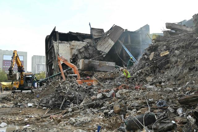 Workers clear debris after a massive fire broke out at a shopping mall in Karachi on January 22, 2026. The death toll from a mall fire in Pakistan's biggest city rose to at least 55 people, a Karachi government official told AFP on January 22. (Photo by Asif HASSAN / AFP)